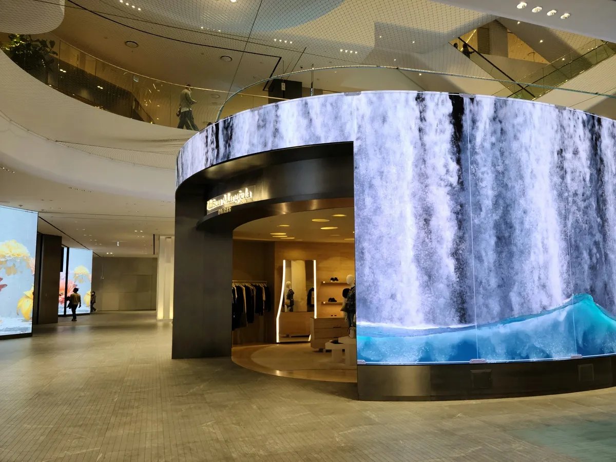 Mur LED courbe affichant une cascade, enroulé autour d'une boutique dans l'atrium d'un centre commercial