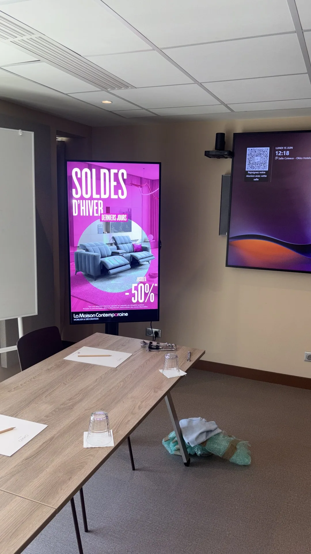 Écran intérieur sur pied installé dans un espace de bureau, diffusant une campagne soldes