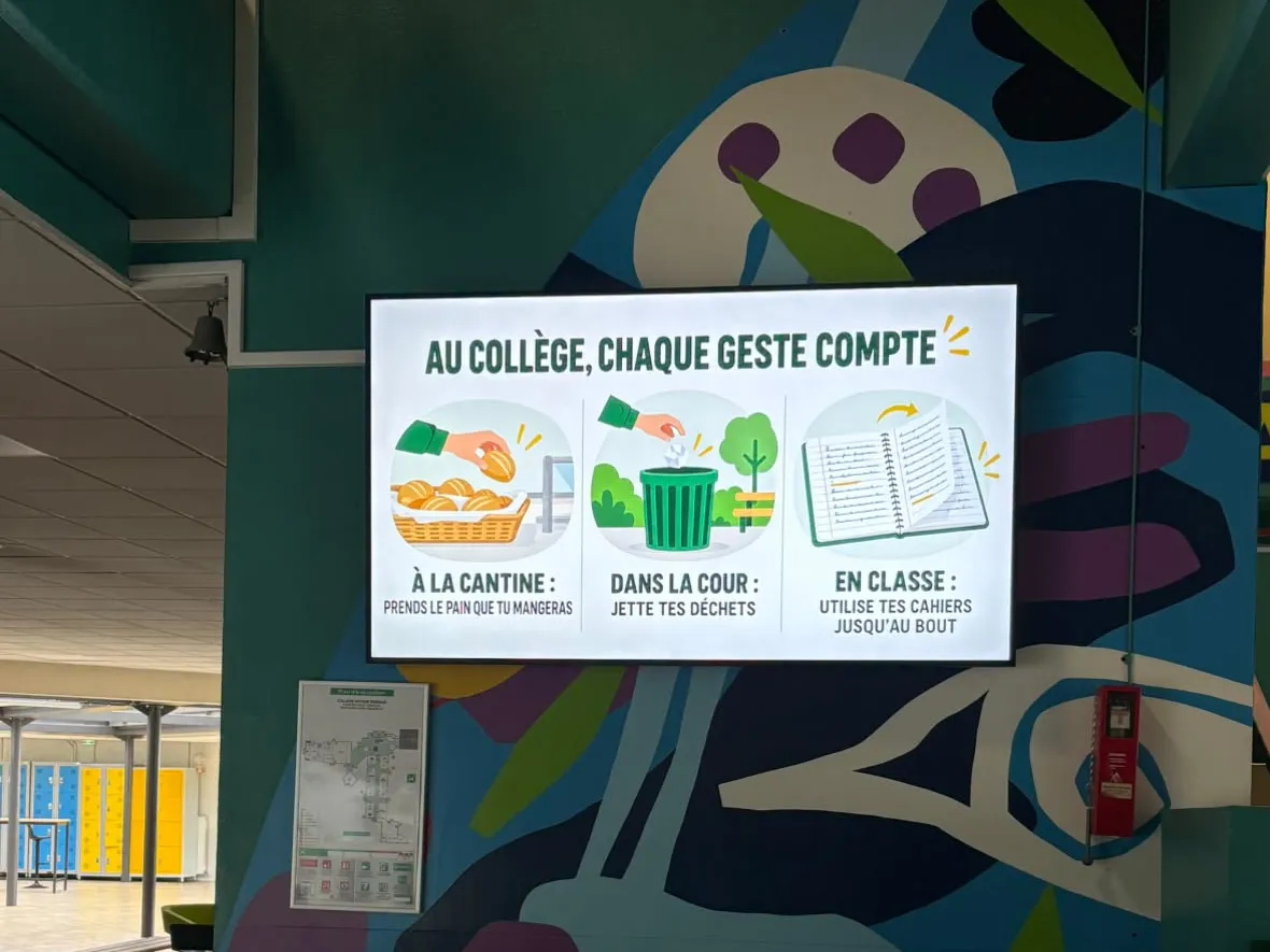 Écran d'information mural dans le hall d'un collège, affichant les éco-gestes à la cantine, dans la cour et en classe